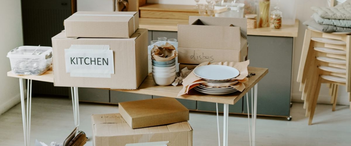 Packing boxes and dishes in kitchen