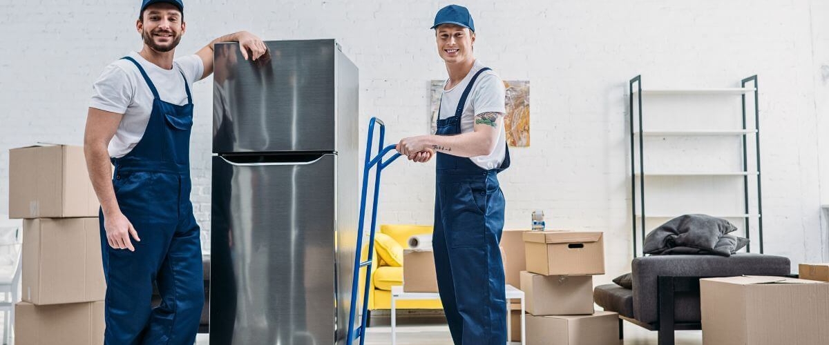 Two removalists moving a fridge